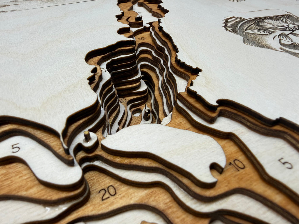 Wooden topographic model with laser-cut details on a white background