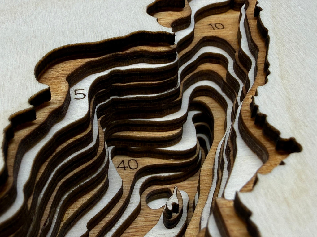 Wooden topographic model with wavy lines and numbers on a light background