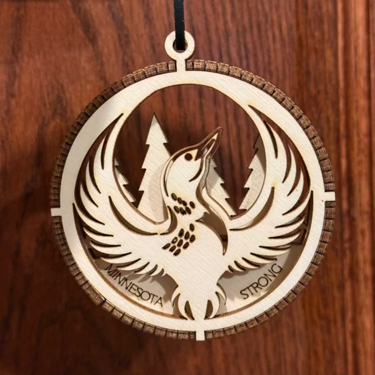 Wooden ornament with bird design and 'Minnesota Strong' text on a wooden background